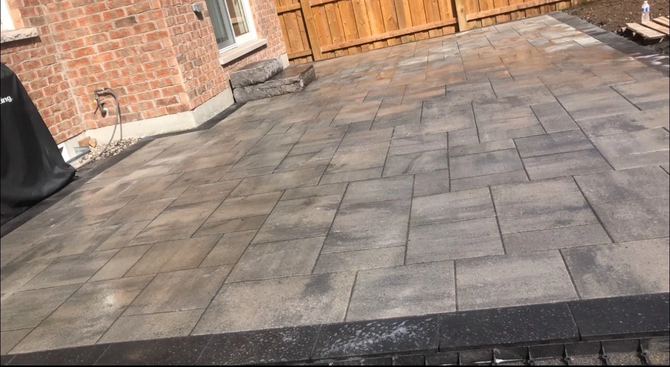 Backyard interlock patio behind a brick home by NS Services