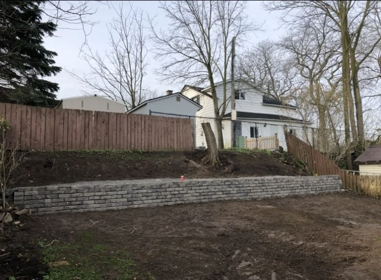 Completed concrete-block retaining wall beneath a timber fence by NS Services
